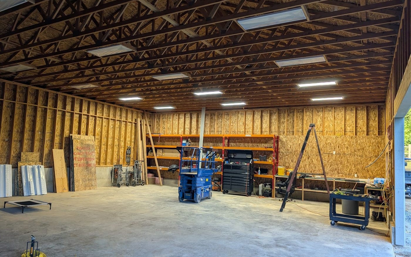 Shop building interior with new LED strip lighting between exposed roof trusses