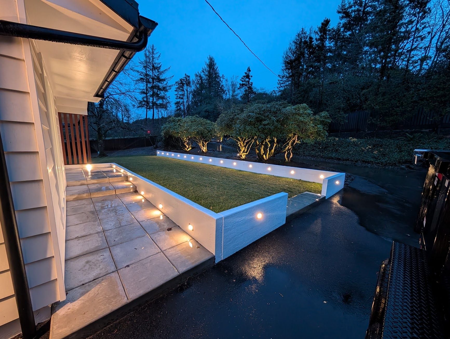 Exterior wall and step lighting glowing at dusk on a landscaped property