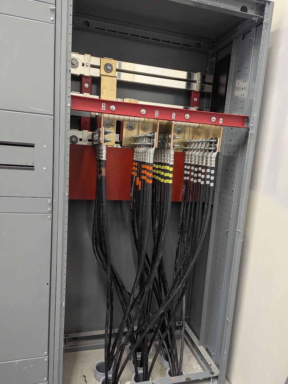 Commercial switchgear cabinet showing copper busbars and phase-taped feeders